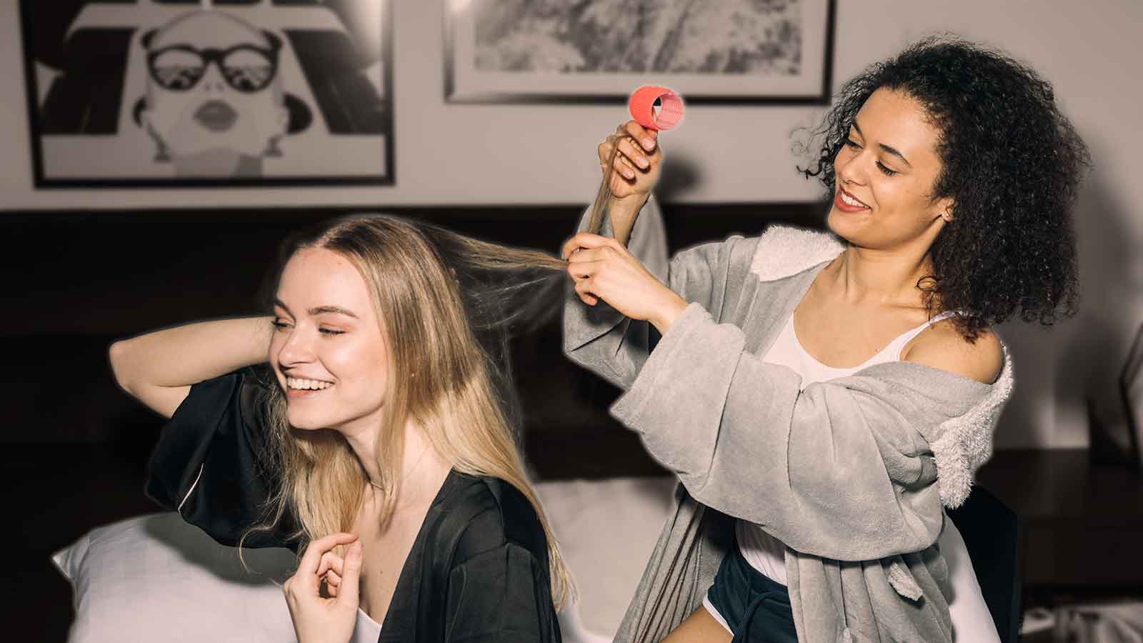 Two friends help each other install hair rollers.